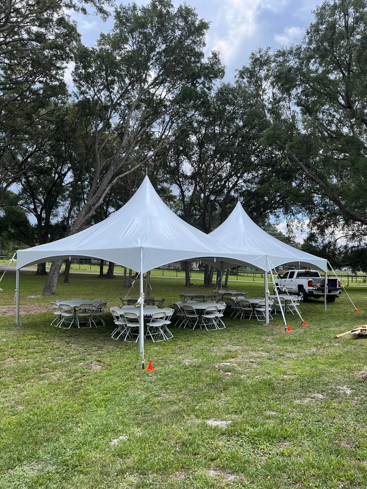 High peak frame tents on grass with round tables set for an outdoor event