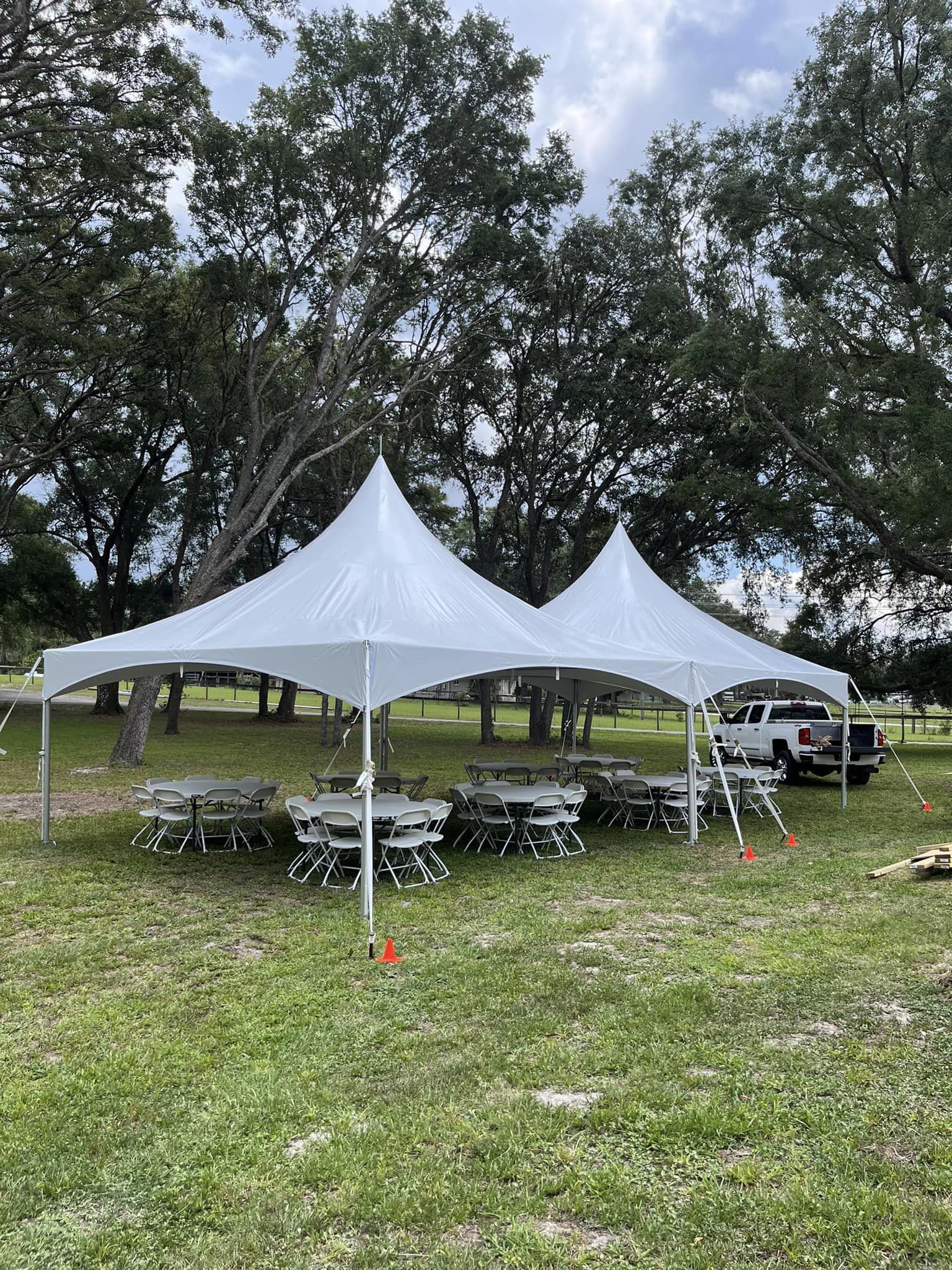 High peak frame tents on grass with round tables set for an outdoor event