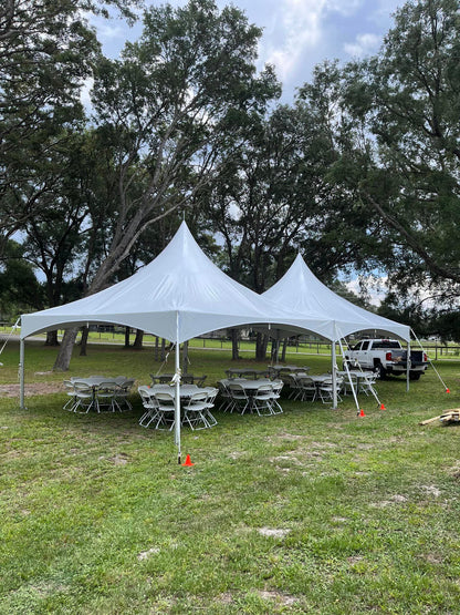 High peak frame tents on grass with round tables set for an outdoor event