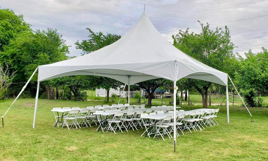 20x20 high peak frame tent set up on grass with white folding tables and chairs underneath